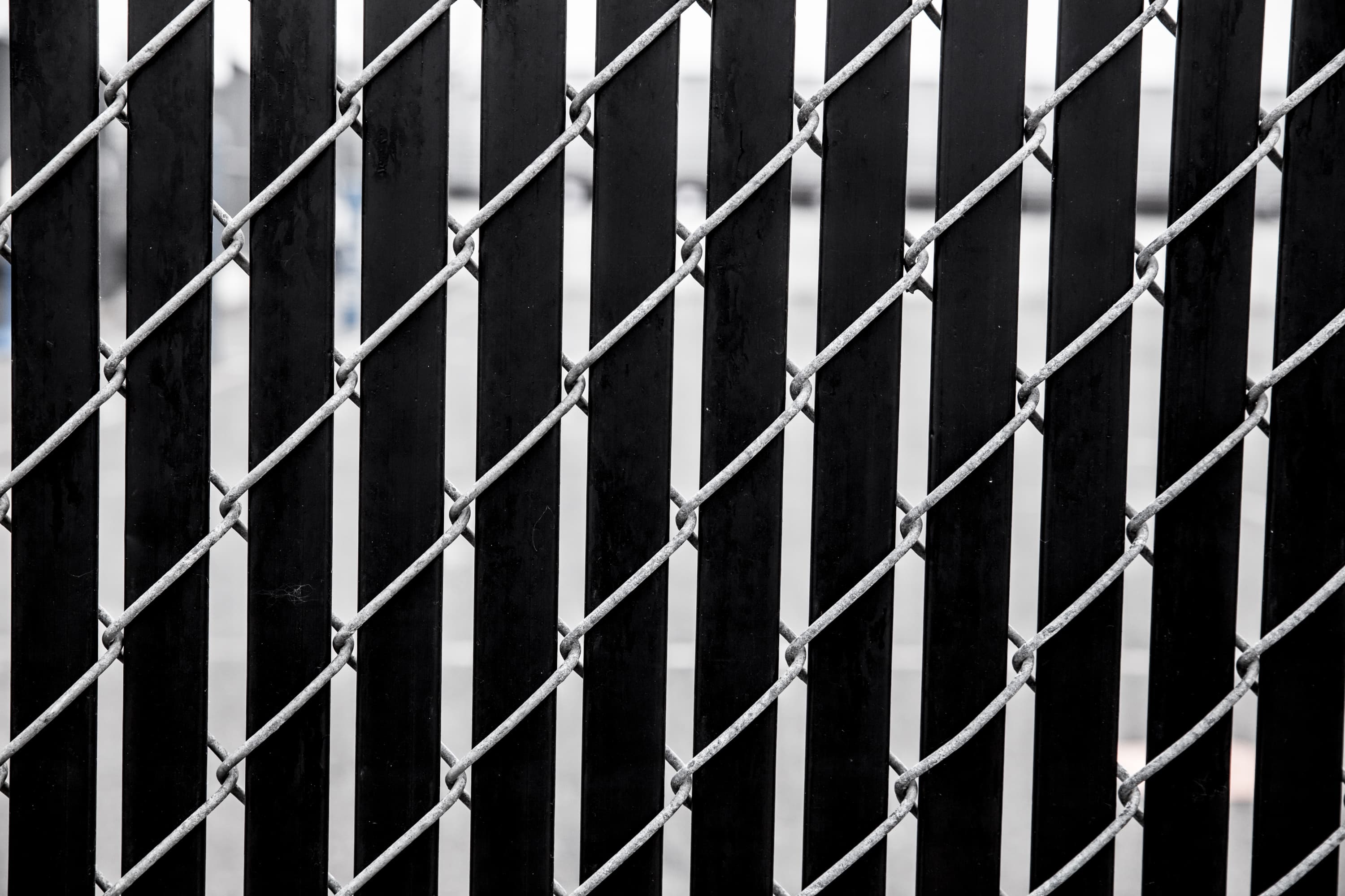 A chain link fence with black slats, close up